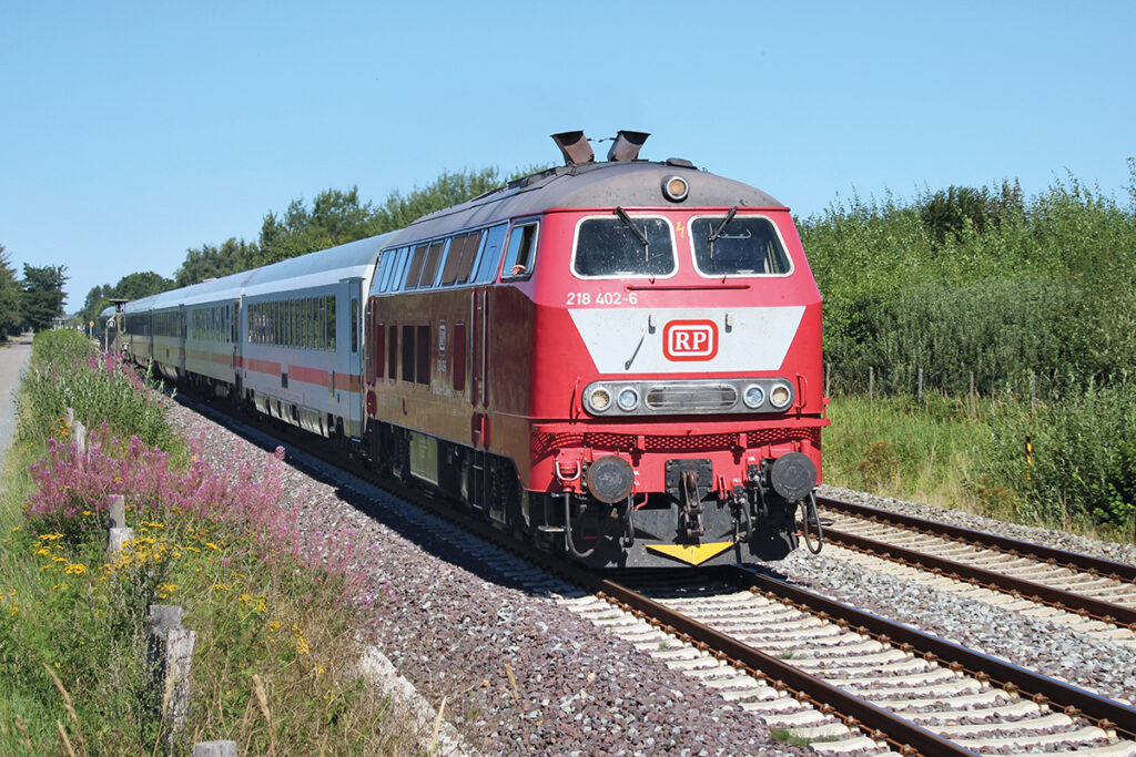 218 402-6 der PR Eisenbahn GmbH zieht ihren Intercity am 12. August 2022 südlich von Niebüll über die erneuerten Gleise.
