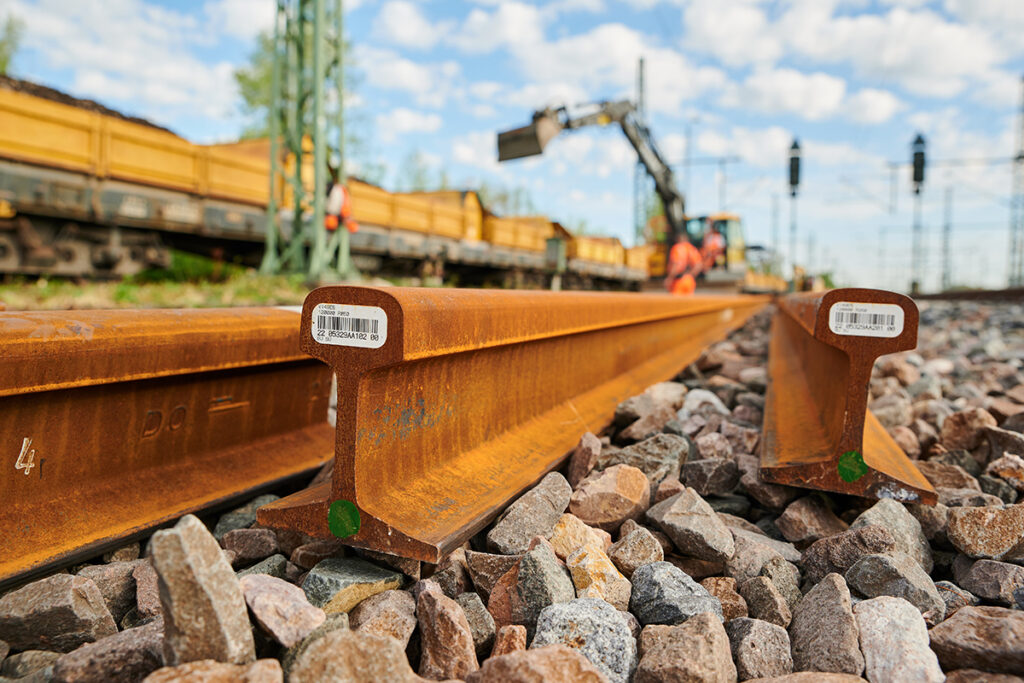 Neue Schienen liegen auf einer Eisenbahn-Baustelle neben dem Gleis.