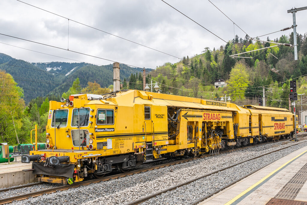 Eine Gleisbaumaschine von Plasser und Theurer steht auf Schienen in Österreich.