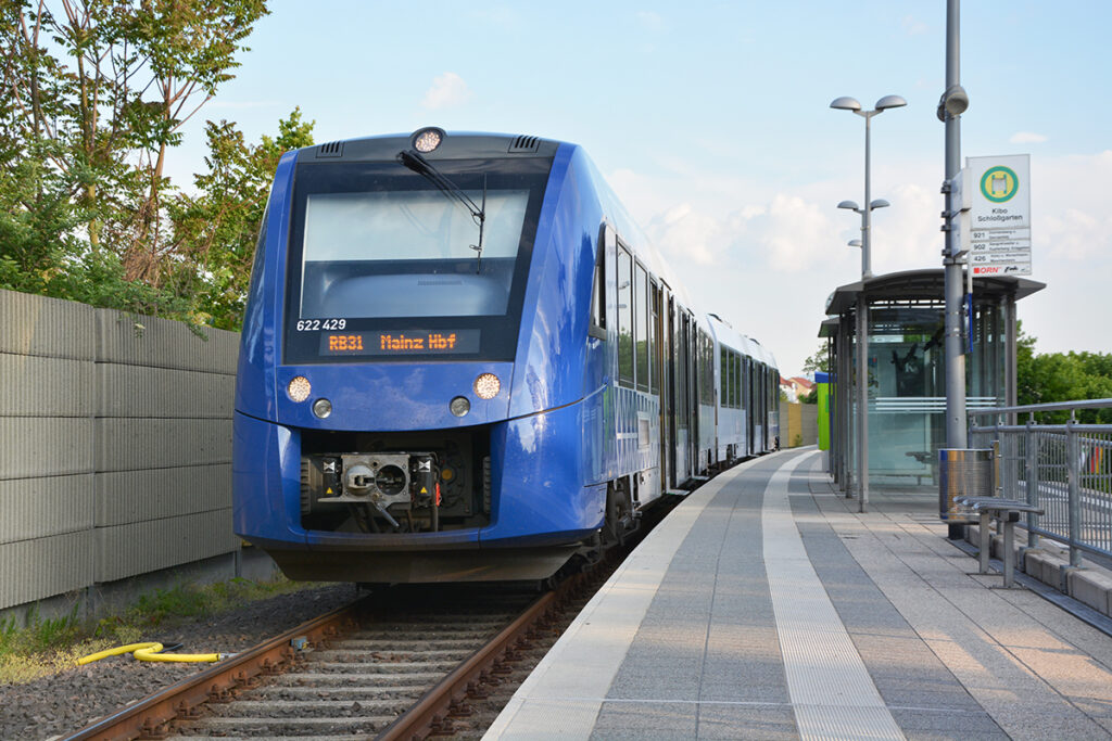 Ein Zug steht auf einem Gleis an einem Bahnsteig.