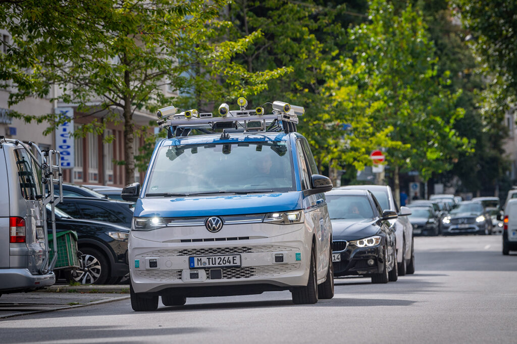 Ein Kleinbus mit Kameras auf dem Dach fährt auf einer Straße.