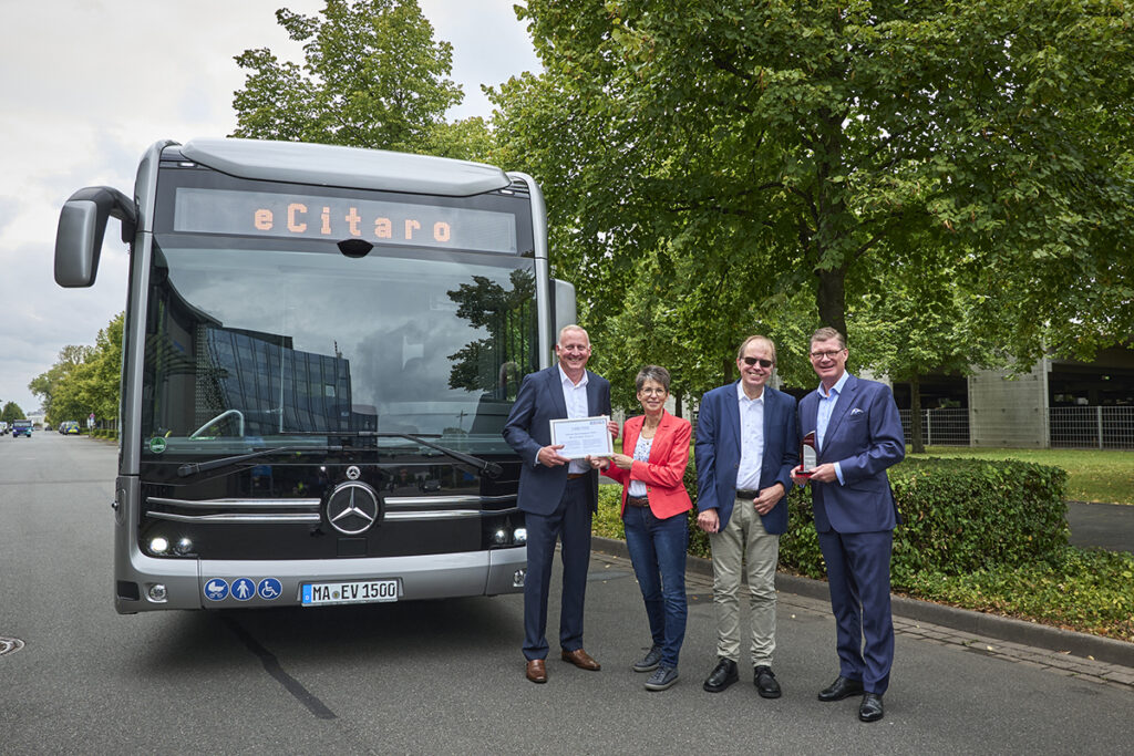 Vier Personen stehen vor einem Elektrobus.