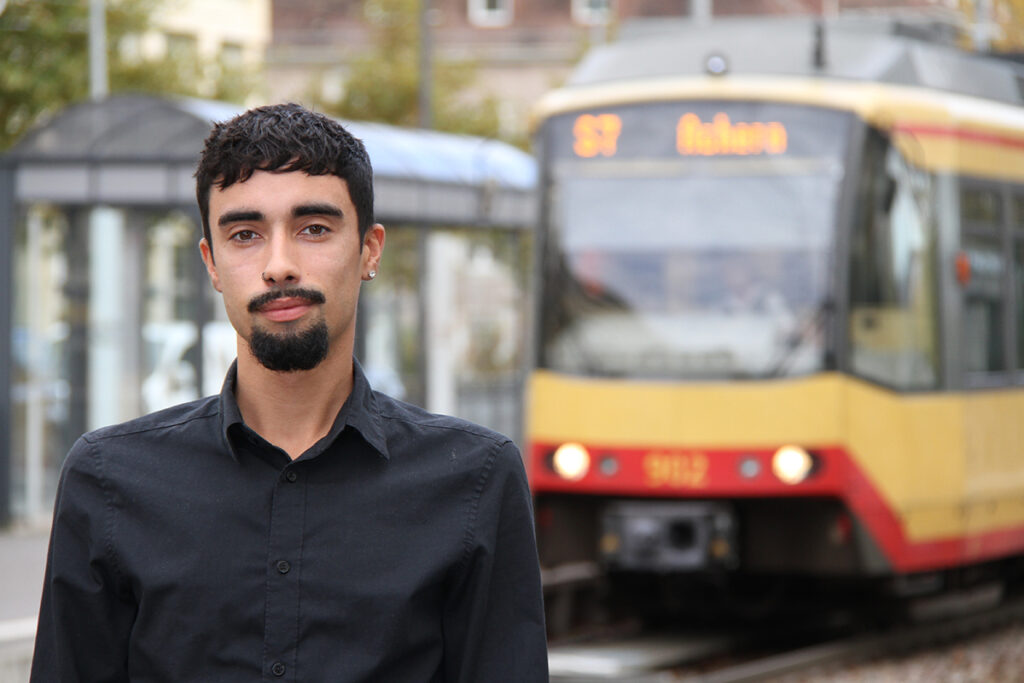 Eine Person steht vor einer Stadtbahn.