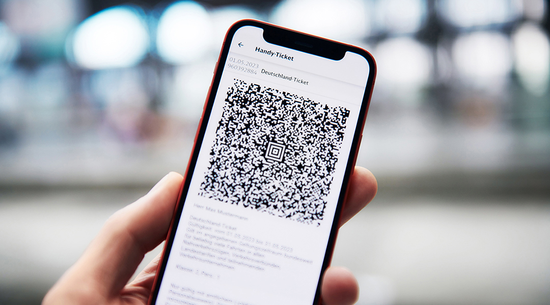 Eine Hand hält ein Handy mit dem Deutschland-Ticket darauf.