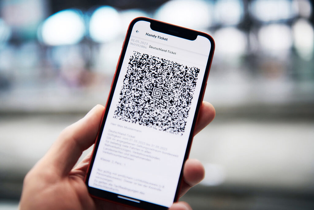 Eine Hand hält ein Handy mit dem Deutschland-Ticket darauf.