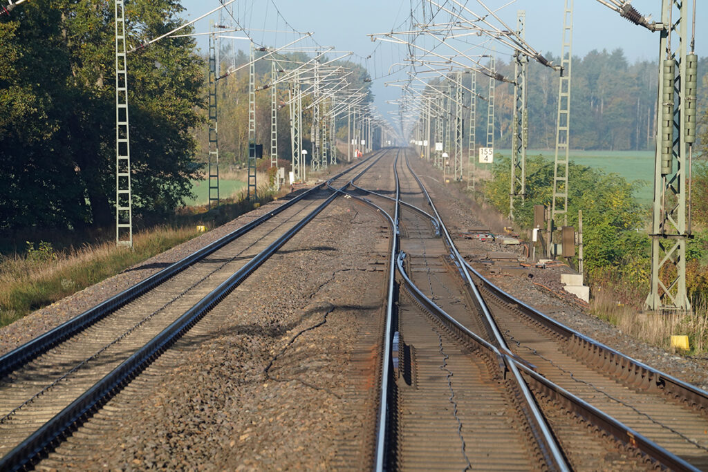 Eine zweigleisige Bahnstrecke führt durch Felder.