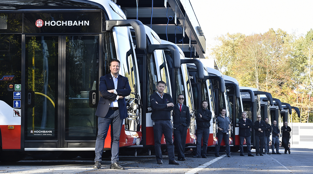 Mehrere Busfahrer der Hochbahn stehen vor Bussen.