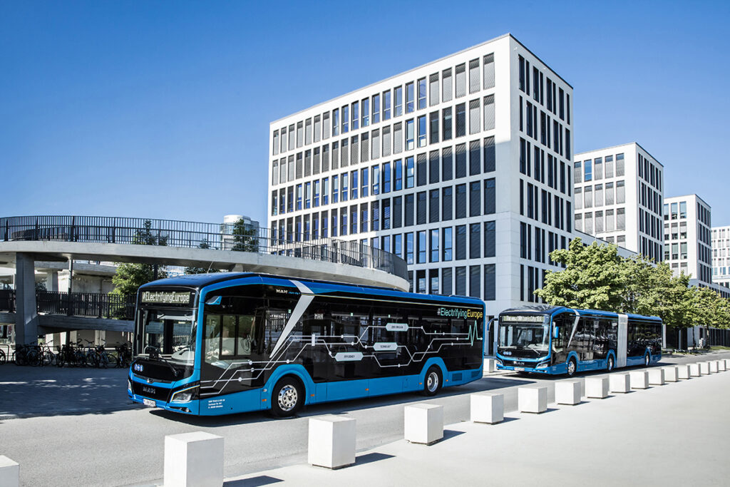 Zwei Elektrobusse von MAN stehen vor Hochhäusern.