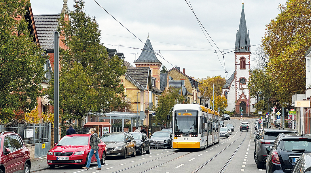 Eine Straßenbahn fährt vor Häusern und einer Kirche.