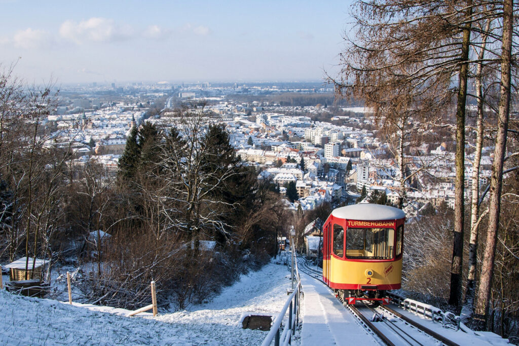 Eine Bergbahn fährt durch einen Wald bergauf.