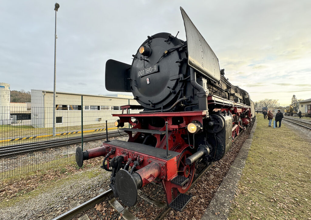 Eine Dampflok steht an einem Bahnsteig.