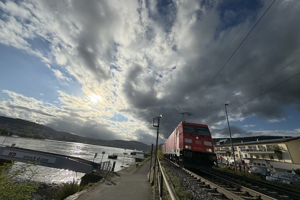 Ein Zug fährt an einem Fluss entlang.