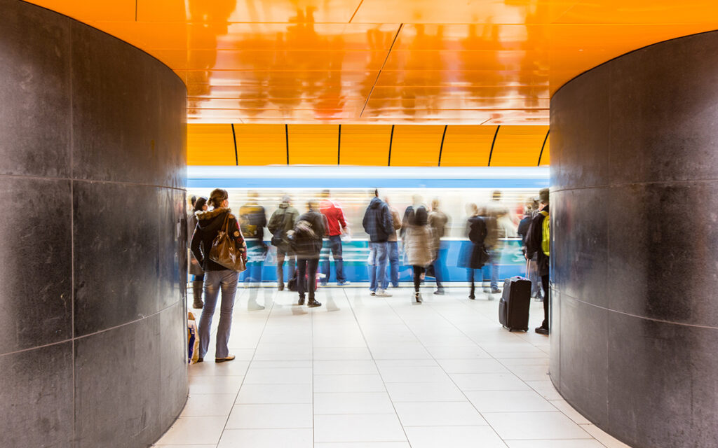 Personen stehen auf einem Bahnsteig in einer Tunnelstation.