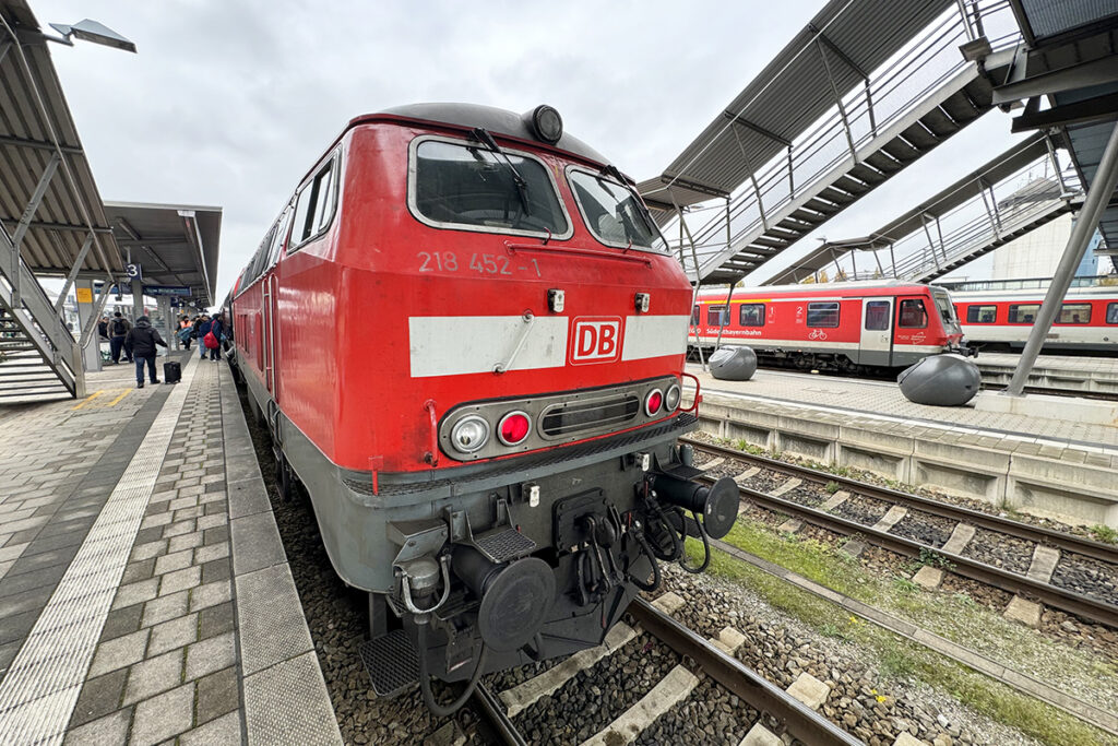 Eine Diesellok steht an einem Bahnsteig.