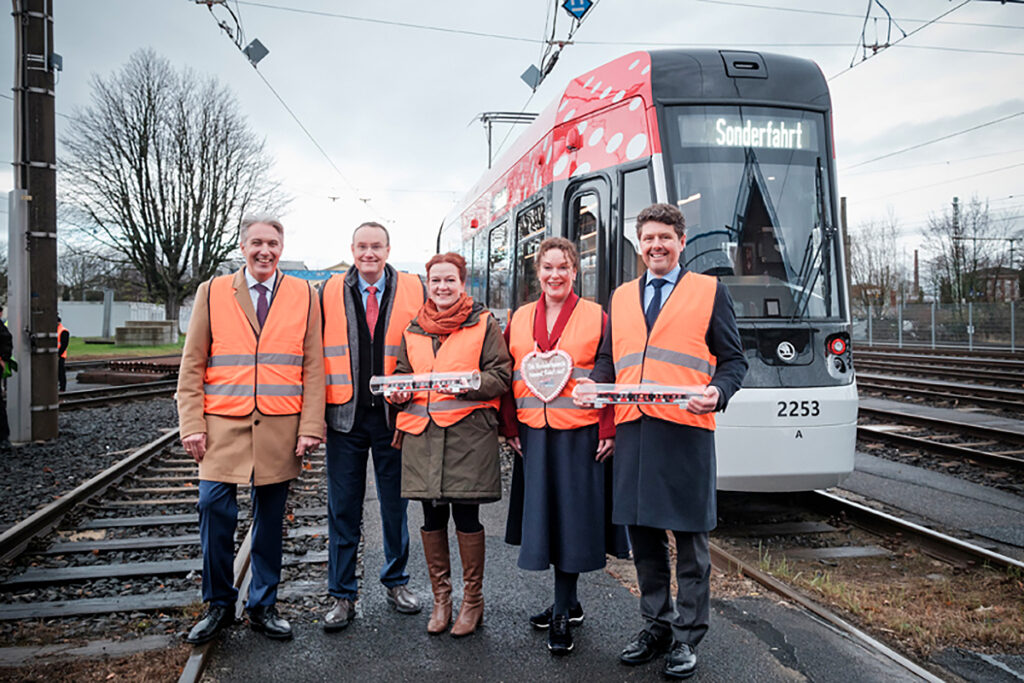 Mehrere Menschen stehen vor einer Straßenbahn für Bonn.