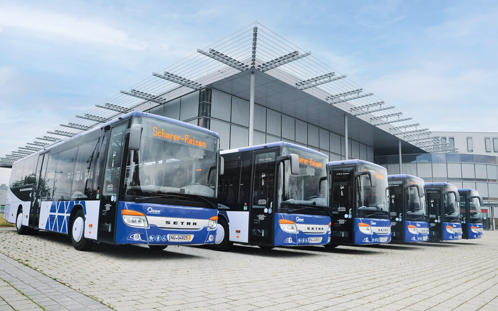 Mehrere Busse stehen vor einer Halle.