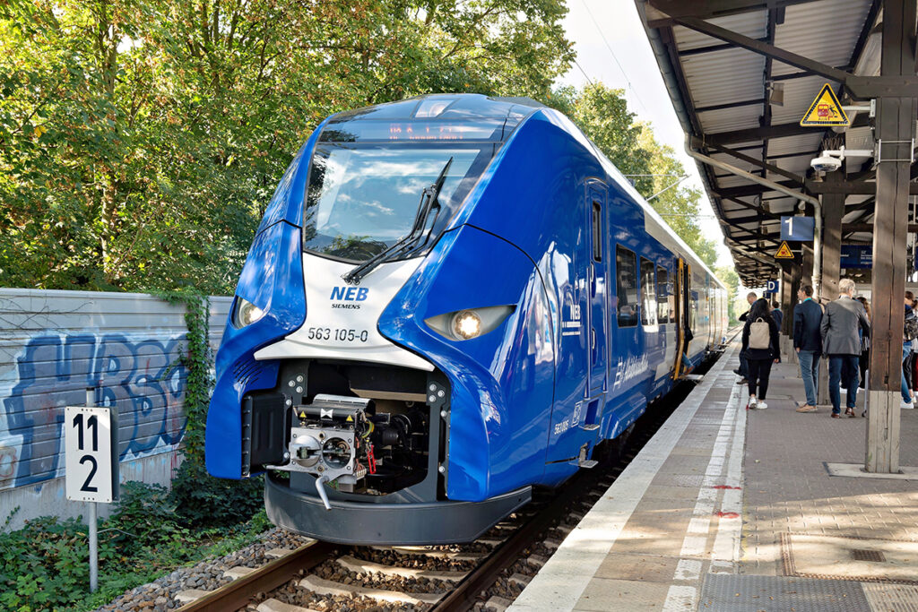 Ein Zug steht an einem Bahnsteig mit Menschen.