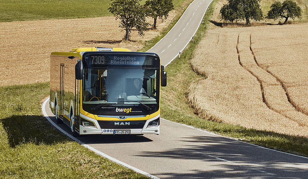 Ein Bus fährt auf einer Straße durch Felder.