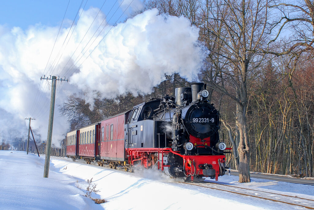 Ein Dampfzug fährt durch eine verschneite Landschaft.