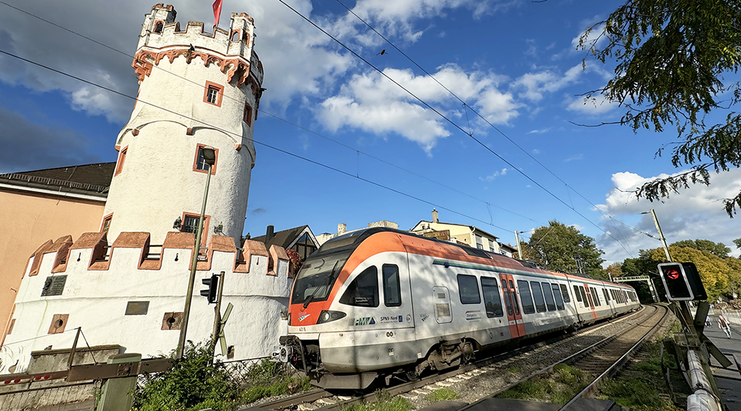 Ein Zug fährt an einem Burgturm vorbei.