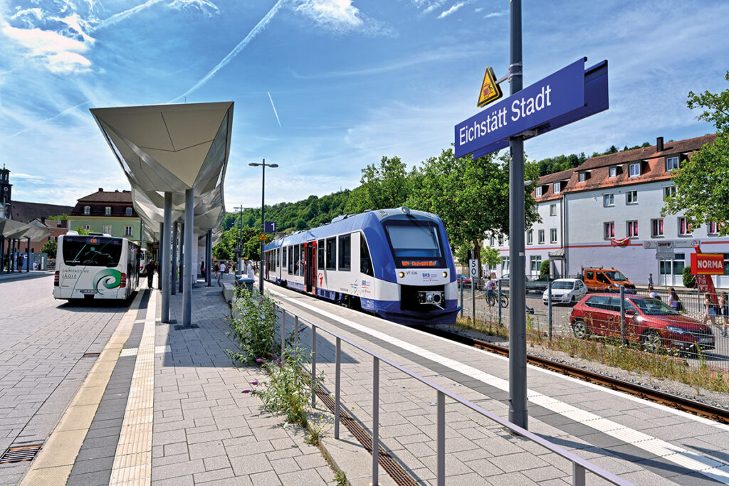 Ein Bus und ein Zug halten an einem gemeinsamen Bahnsteig.