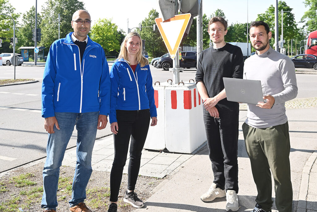 Vier Personen stehen vor einer Ampelanlage.