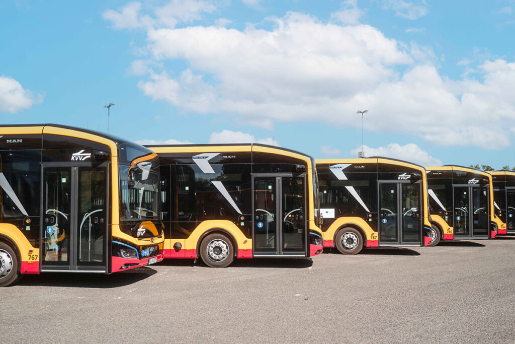 Elektrobusse stehen nebeneinander auf einem Platz.