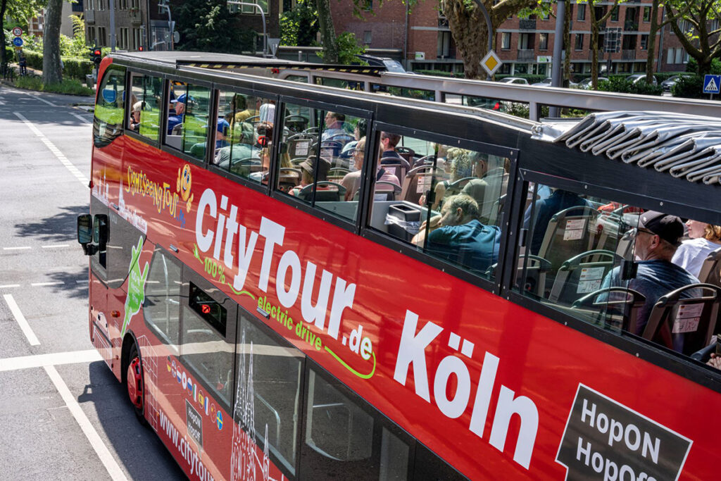 Personen sitzen in einem Doppeldecker-Bus mit offenem Dach.