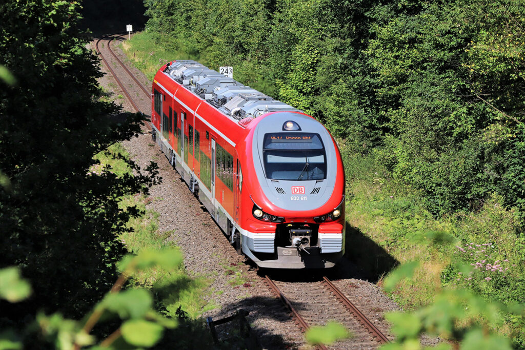 Ein Zug fährt vor Bäumen entlang.