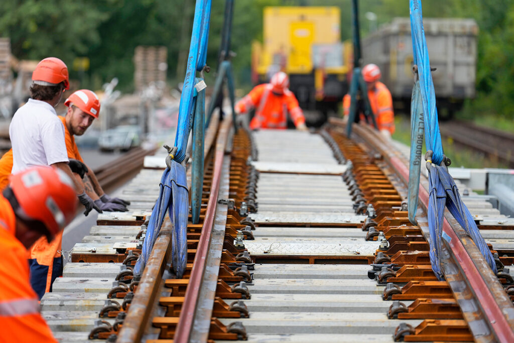 Mehrere Personen stehen neben einer Weiche, die an einem Kran hängt.