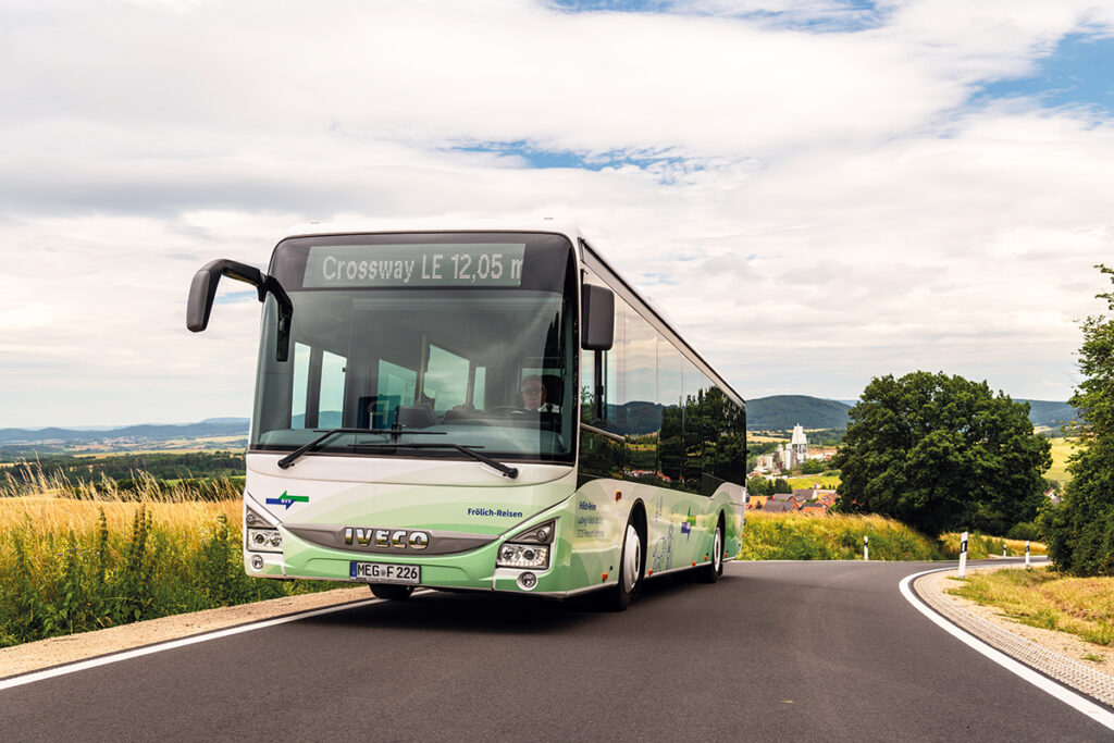 Ein Bus fährt auf einer Straße durch Hügel.