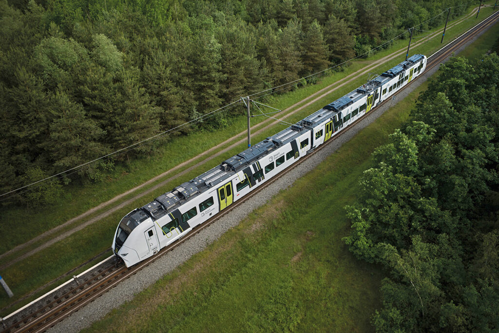 Ein Zug des Typs Mireo Smart fährt durch einen Wald.