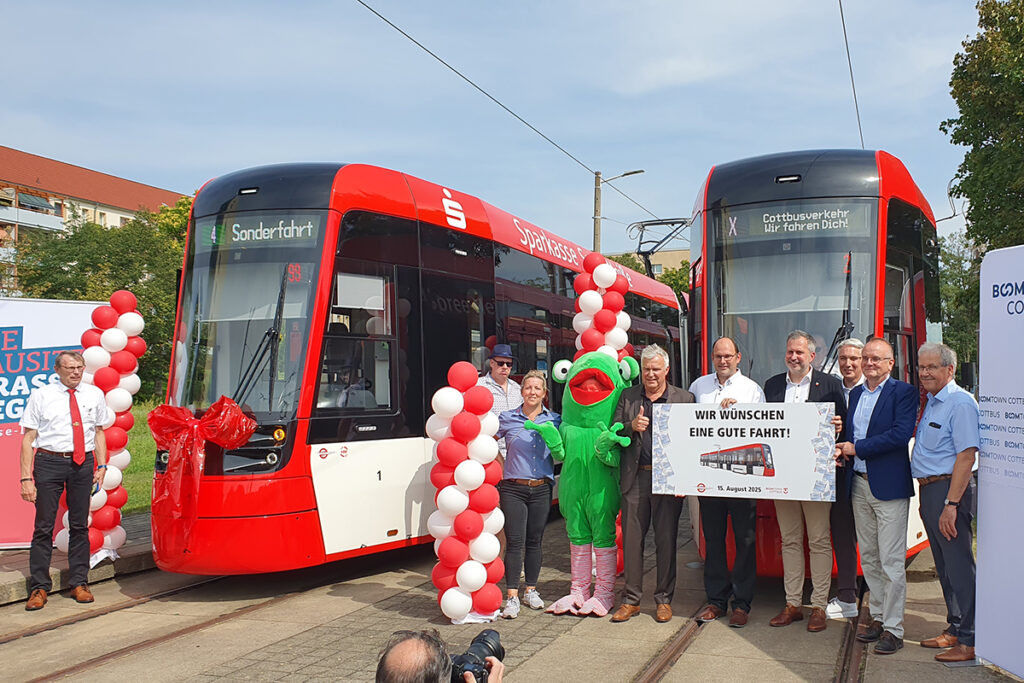 Mehrere Personen stehen vor zwei Straßenbahnen.