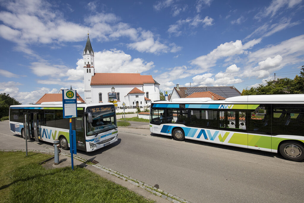 Zwei Busse stehen auf einer Straße vor einer Kirche.