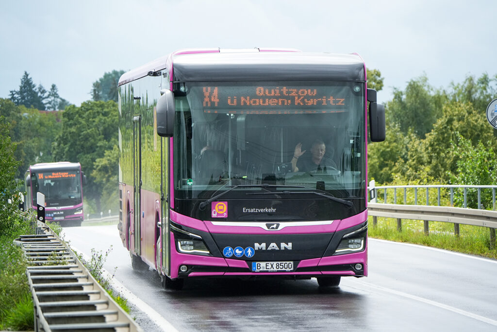Zwei Busse fahren hintereinander auf einer Straße.