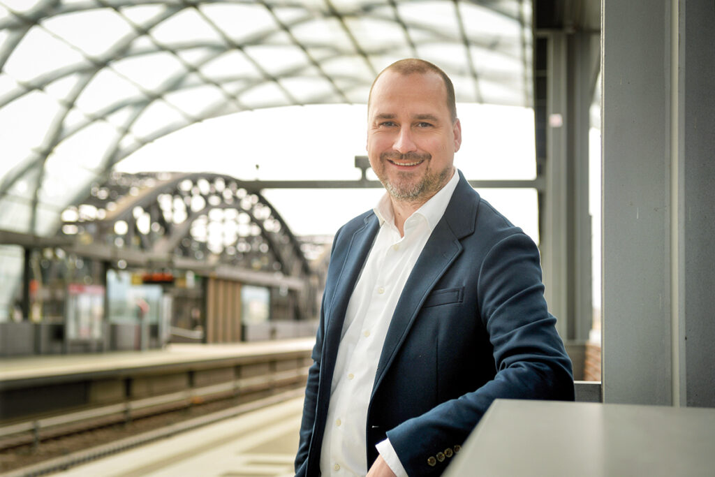 Porträtaufnahme einer Person auf einem Bahnsteig.