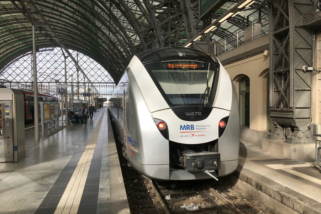 Ein Zug steht an einem Bahnsteig in einer Bahnhofshalle.