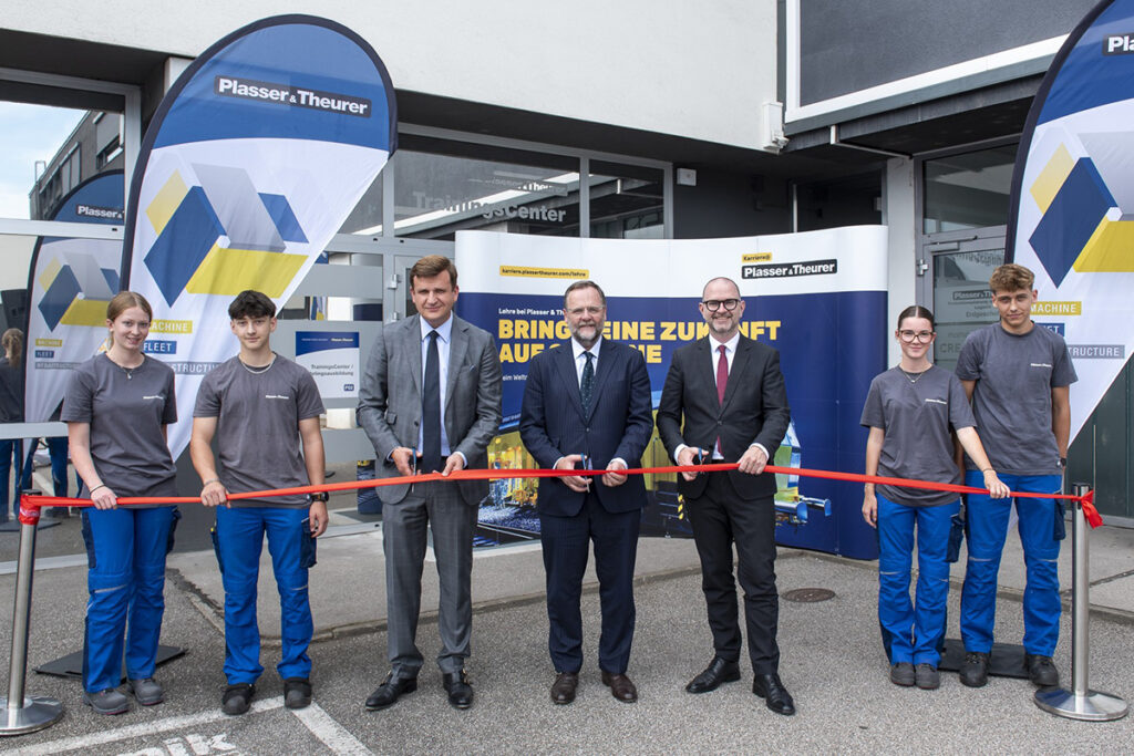 Mehrere Personen stehen hinter einem Band, das mit einer Schere durchschnitten wird.