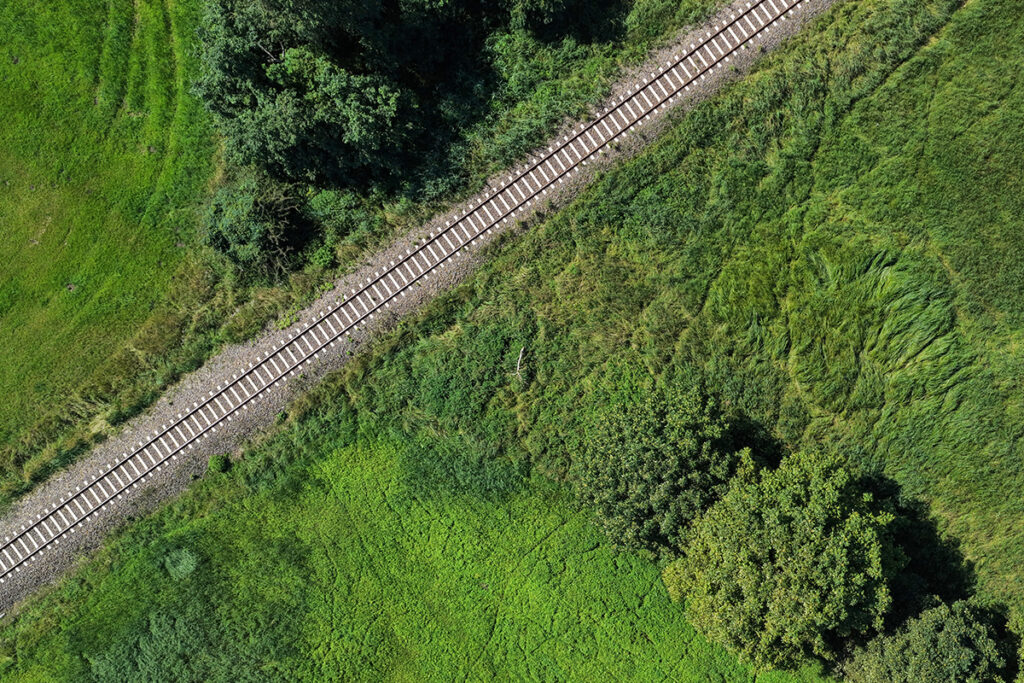 Ein Gleis führt durch eine grüne Wiese.