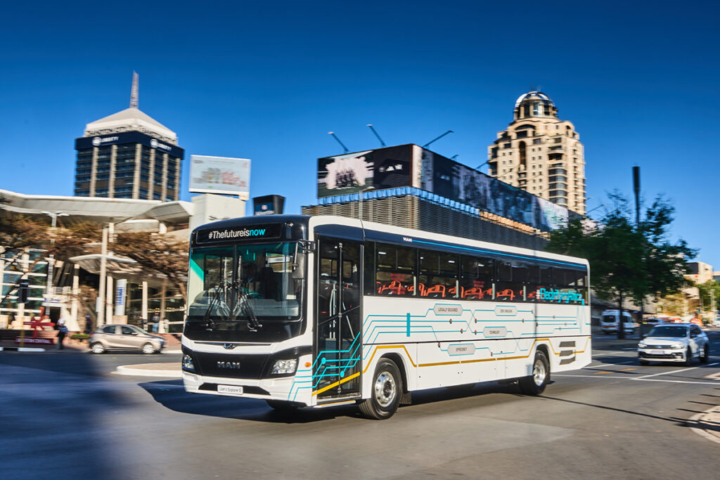 Ein Bus fährt auf einer Straße vor Häusern entlang.