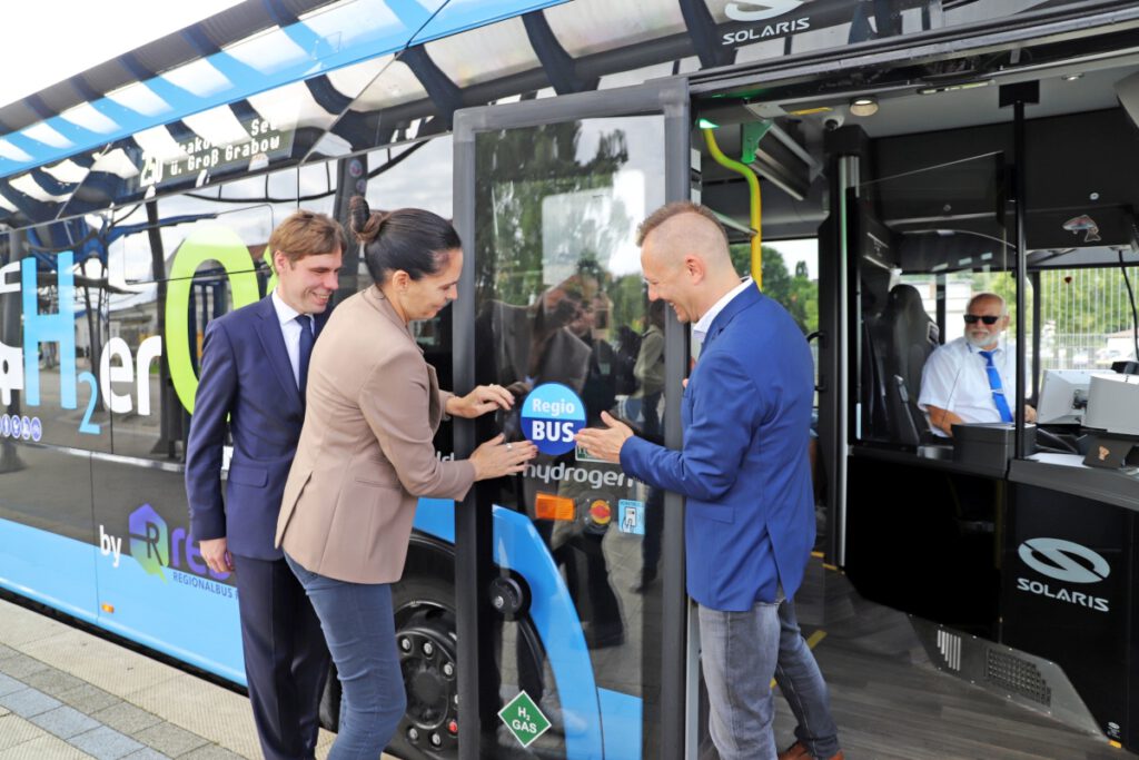 Mitarbeitende kleben ein Regiobus-Schild an der Tür eines Busses