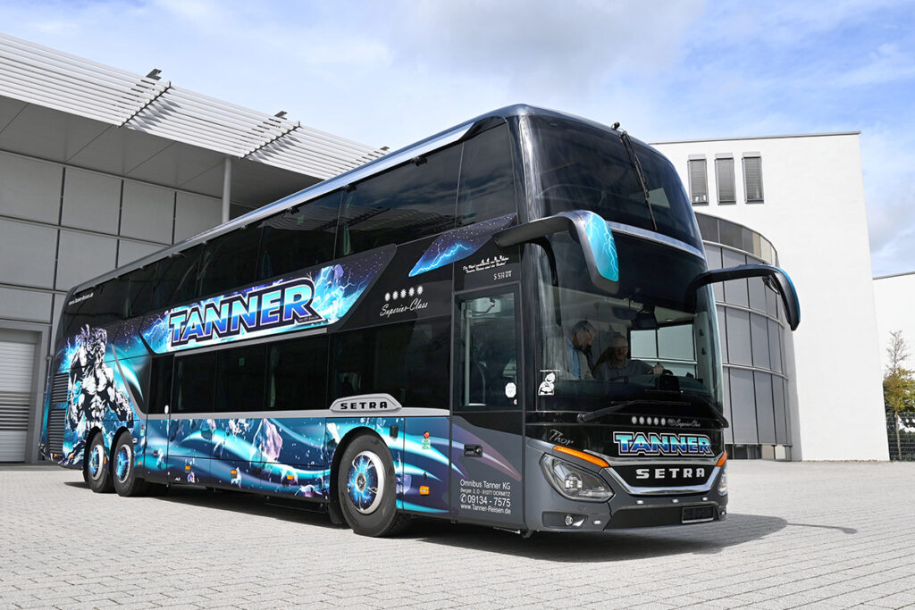 Ein Doppelstockbus steht vor einer Halle.