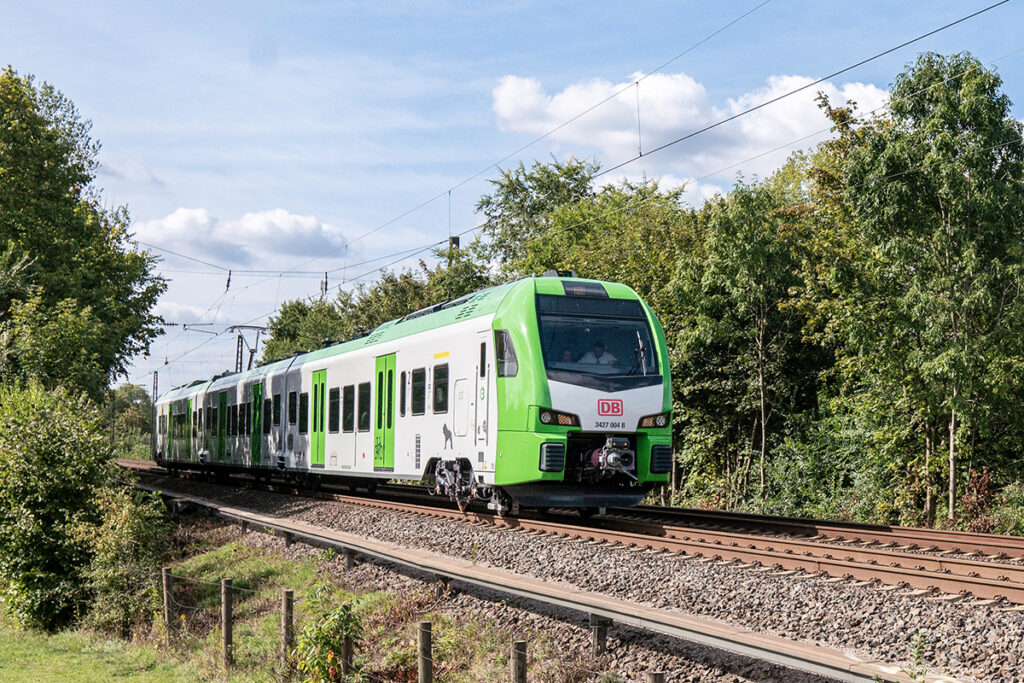 Ein Triebzug der S-Bahn Rhein-Ruhr fährt auf einer Strecke vor Bäumen.