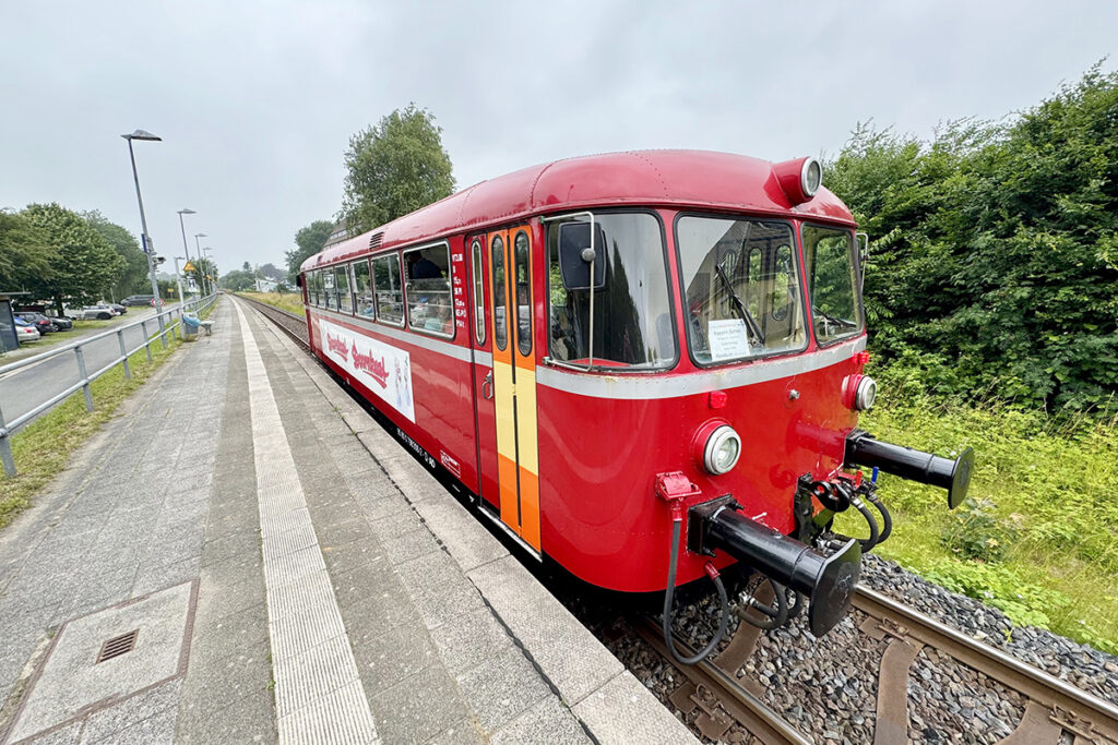 Ein Schienenbus steht an einem Bahnsteig.