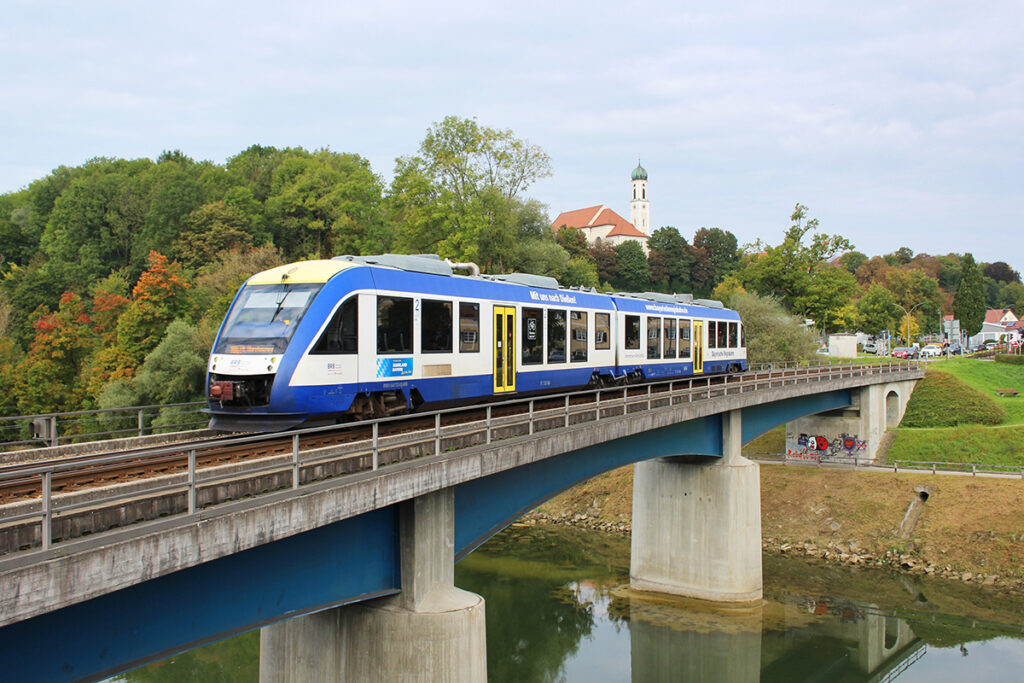 Ein Triebzug fährt auf einer Brücke über einen Fluss.