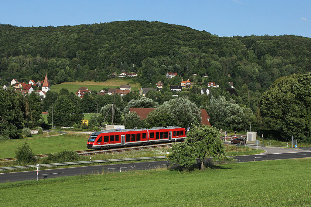 Ein Triebzug der Deutschen Bahn fährt durch ein bewaldetes Tal.