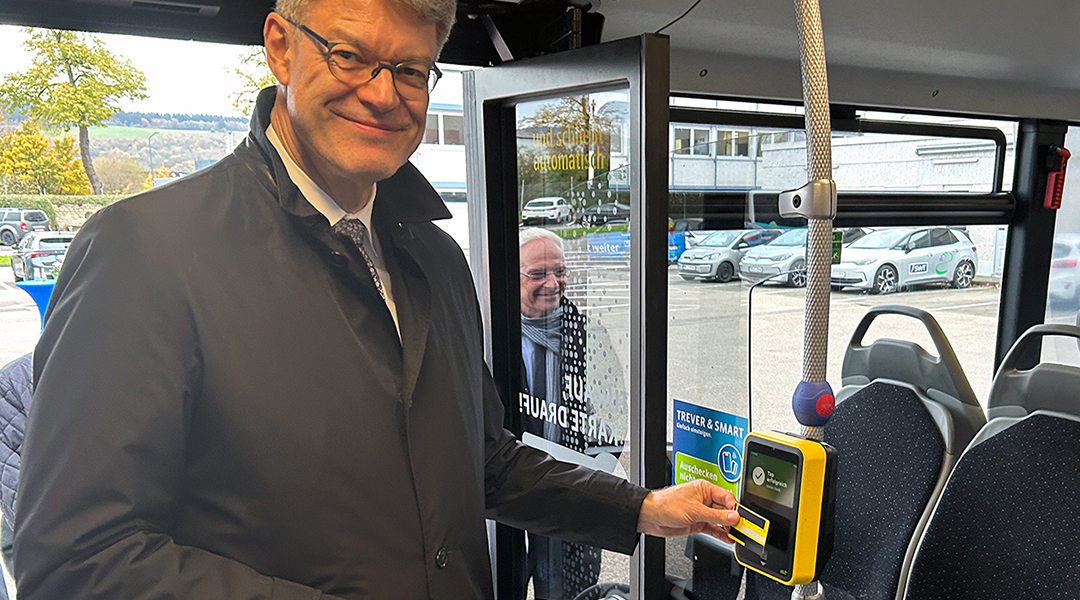 Verkehrsminister Schnieder hält eine Kreditkarte an ein Lesegerät im Bus.