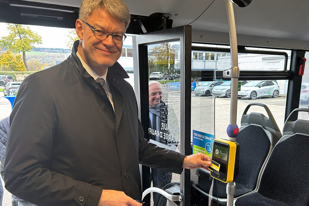 Verkehrsminister Schnieder hält eine Kreditkarte an ein Lesegerät im Bus.