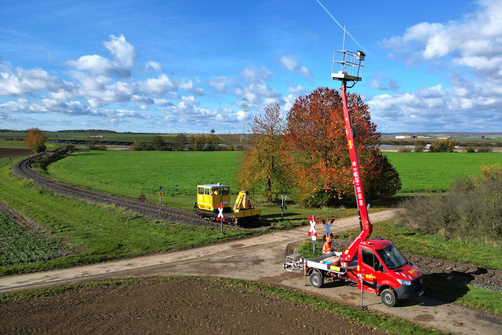 Ein Messefahrzeug und ein Gleiskraftwagen stehen an einer Bahnstrecke.