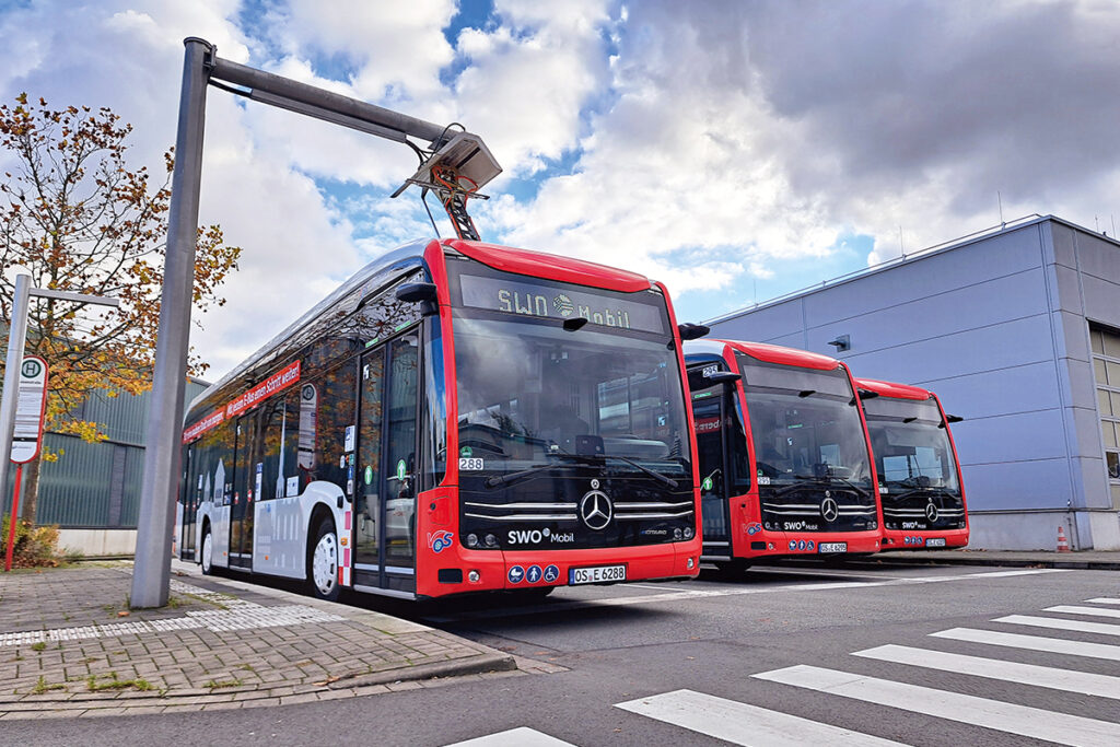 Drei Elektrobusse stehen an einer Ladestation.